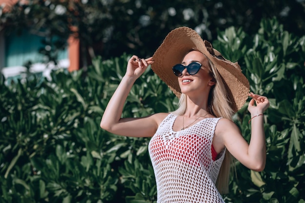 Modeporträt. Lächelnde blonde Frau im modischen Look. Meer-Stil. Auf Naturhintergrund. Stil und heißes Mädchen im Freien. Frau mit Sonnenbrille und Strohhut. Mode.