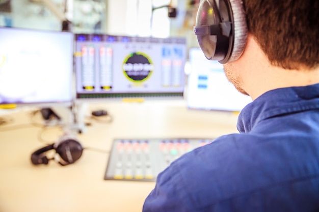 El moderador de radio está sentado en un estudio de transmisión moderno y habla por el micrófono