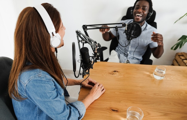 Moderatoren, die gemeinsam eine Podcast-Sitzung haben - Sprecherin, die während des Live-Streams ein Interview führt - Konzept der Technologietrends - Fokus auf linkes Mikrofon