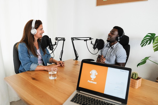 Moderatoren mit gemeinsamer Podcast-Sitzung - Multirassische Sprecher, die während des Live-Streams ein Interview führen - Fokus auf weiblichem Gesicht