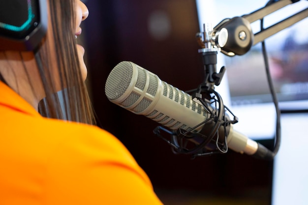 Moderatorin überträgt ihren Podcast live mit professionellem Mikrofon und Kopfhörern in einem kleinen Streaming-Studio
