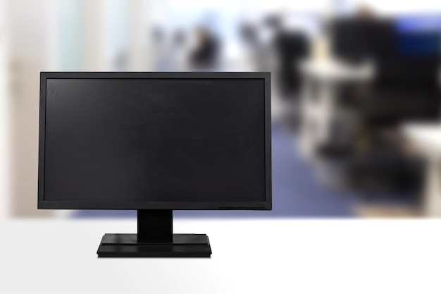 A modern black computer monitor on a white desk in an office setting