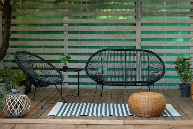 Moderna casa adosada con plantas, pared y mesa de madera, cómodo sofá, sillón y farolillos