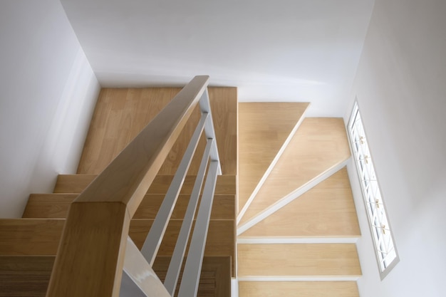 La moderna escalera de madera curvada con pasamanos de metal blanco en la casa urbana