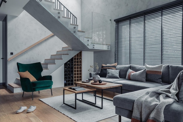 Moderna sala de estar design de interiores Sofá de canto cinza poltrona de veludo mesa de centro e acessórios pessoais minimalistas escadas no interior da sala de estar Paredes de concreto Modelo