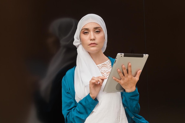 Moderne arabische muslimische Frau mit Tablet-Computer im Freien
