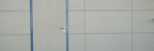 Moderne Bürolobby mit Holzwänden, brauner Tür, weißer Wand und vertikalem Poster
