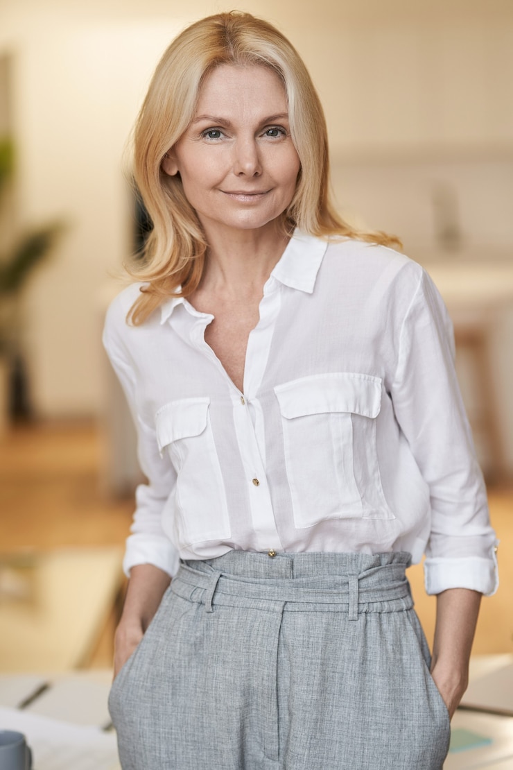 Foto moderne dame smart reife geschäftsfrau mit blonden haaren in die kamera schaut, während sie drinnen steht