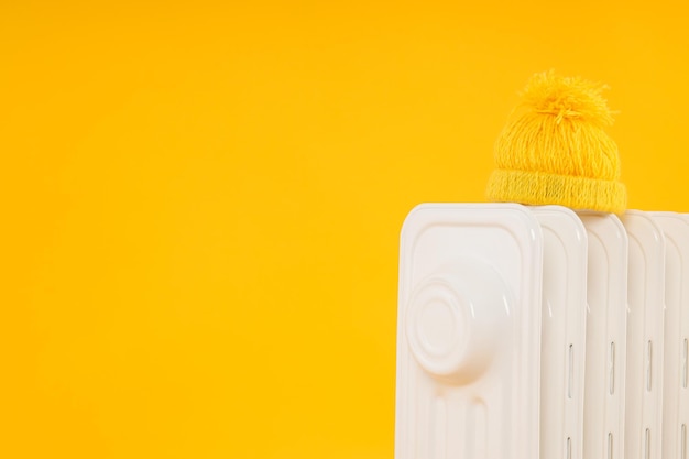 Moderne Elektroheizung mit Hut auf gelbem Hintergrund