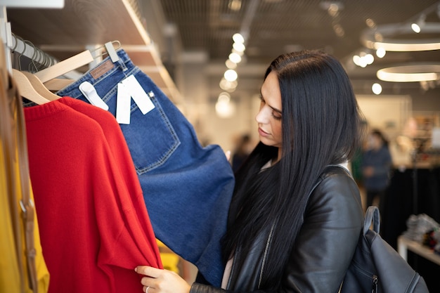 Moderne Frau, die Kleidung im modischen Shop-Boutique-Rabatt auswählt und Freizeithobby genießt