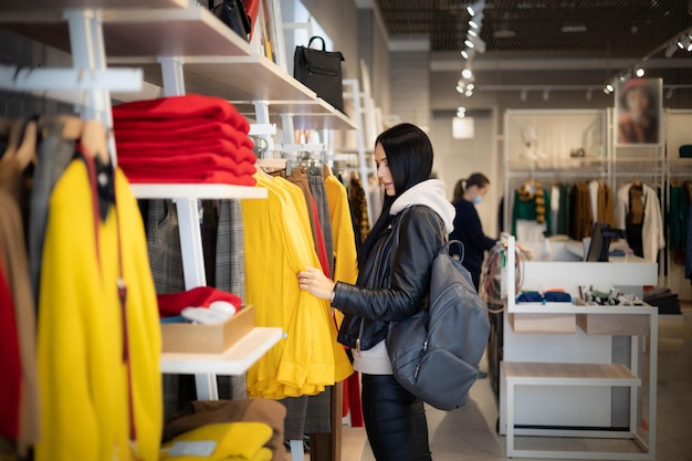 Moderne Frau, die Kleidung im modischen Shop-Boutique-Rabatt auswählt und Freizeithobby genießt