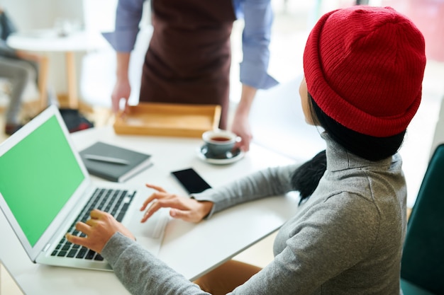 Moderne Frau, die Laptop im Café verwendet