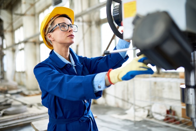 Moderne Frau, die Maschinen in der Fabrik einstellt