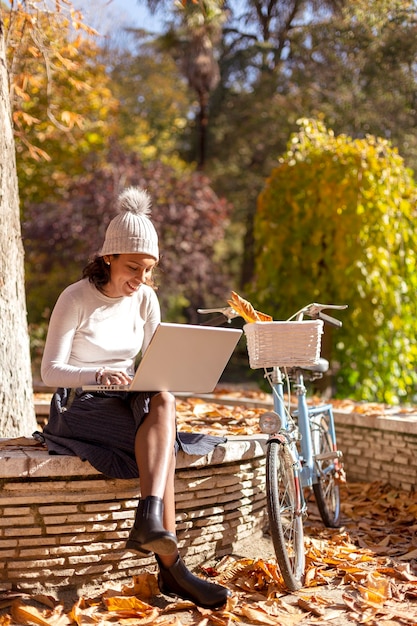 Moderne Frau, die mit ihrem Laptop draußen verwendet.