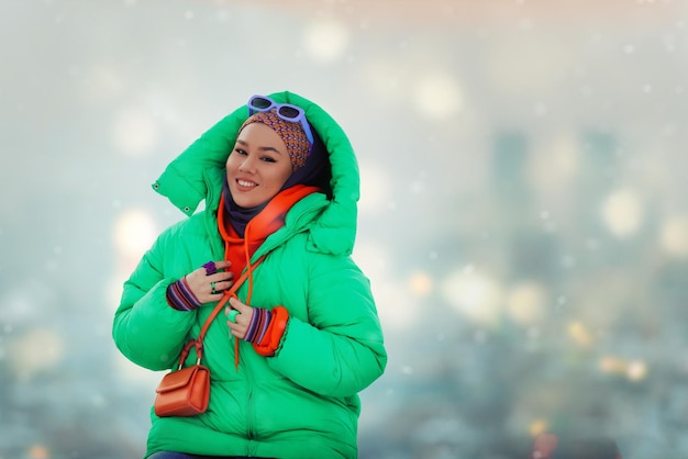 Moderne Frau im Hijab mit grüner Jacke posiert an einem Wintertag