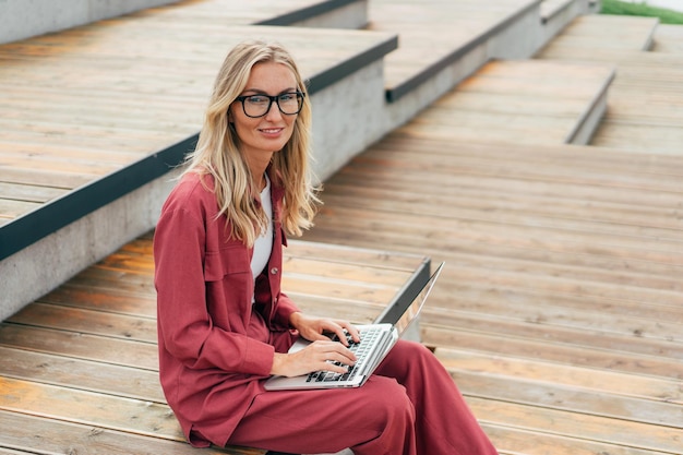 Moderne Geschäftsfrau arbeitet in einem öffentlichen Park mit einem Laptop aus der Ferne