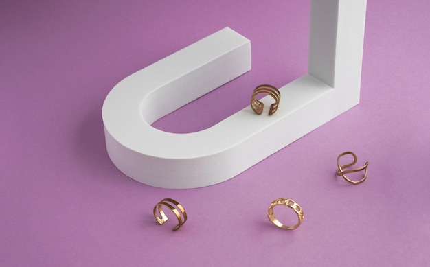 Moderne goldene Ringsammlung auf weißem u-förmigem Podium und violettem Hintergrund mit Kopierraum