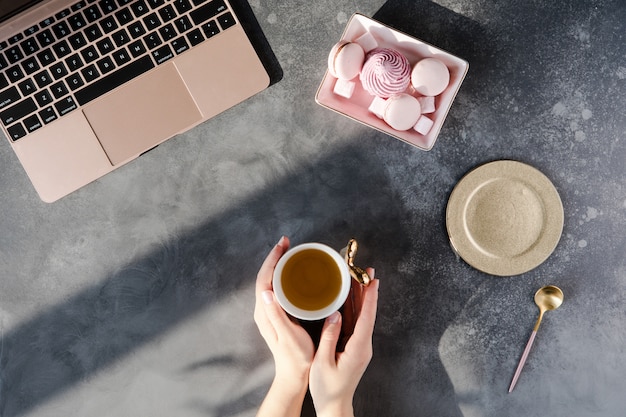 Moderne graue Schreibtischtabelle mit Laptop, andere Versorgungen mit Tasse Tee.