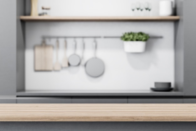 Moderne helle Holztischplatte mit Copyspace für Ihren Text bei verschwommenen Küchenutensilien und Geschirr auf grauem Wandhintergrund 3D-Rendering-Mock-up