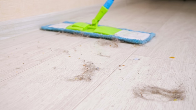 Foto moderne holzböden von haarfetzen, staub und schmutz mit weichem mopp im raum während des aufräumens reinigen