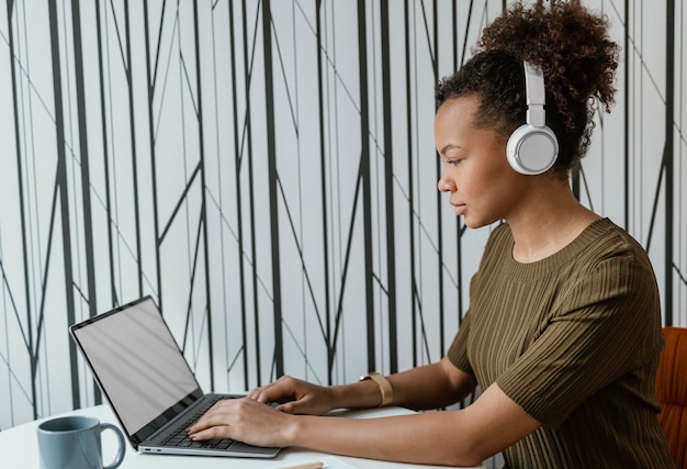 Moderne junge Frau, die von zu Hause auf ihrem Laptop arbeitet