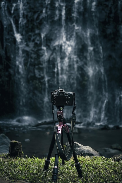 Moderne Kamera ist auf Stativ für Landschaftsfotografie vor Wasserfall eingestellt