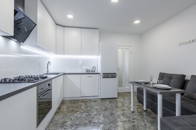 Moderne küche in hellen weißtönen mit schwarzen marmorfliesen auf dem boden in einer kleinen wohnung