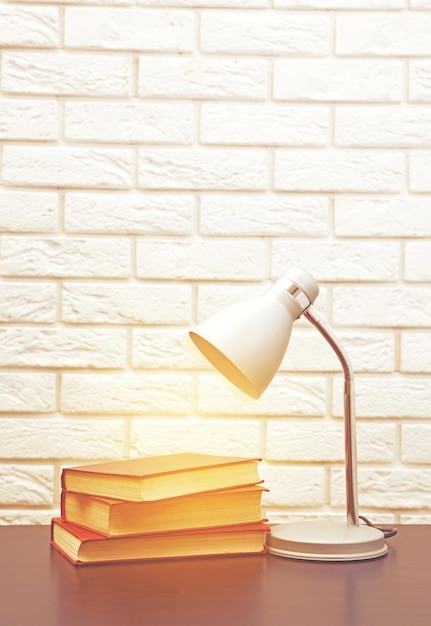 Moderne Lampe und Bücher auf dem Schreibtisch auf weißem Wandhintergrund