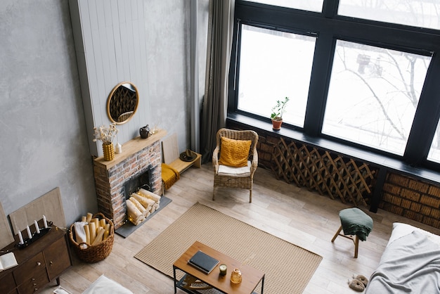 Moderne Landhausvilla im skandinavischen Stil, graues minimalistisches Interieur mit Kamin und weißer Stuckwand. Blick auf das Wohnzimmer von oben, vom zweiten Stock