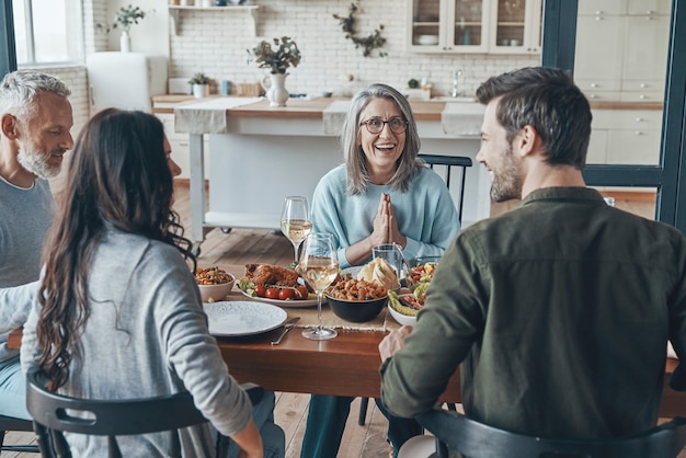 Moderne Mehrgenerationenfamilie, die beim gemeinsamen Abendessen kommuniziert und lächelt