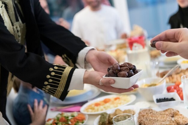 moderne multiethnische muslimische Familie, die sich eine Schüssel mit Datteln teilt, während sie während eines Ramadan-Festes zu Hause gemeinsam ein Iftar-Abendessen genießen.