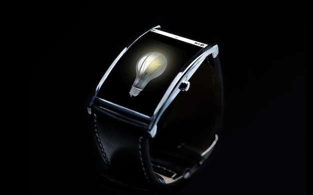 Moderne Technologie, Idee, Objekt und Medienkonzept - Nahaufnahme einer schwarzen Smartwatch mit Glühbirnensymbol auf dem Bildschirm