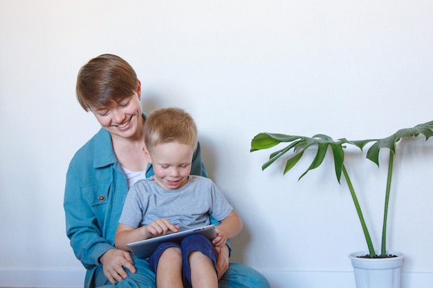 Moderne Technologien im Alltag Eine Frau und ein Kind betrachten ein Tablet auf dem Boden.