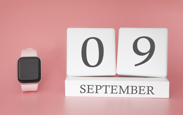 Moderne Uhr mit Würfelkalender und Datum 09. September auf rosa Wand. Konzept Herbstzeit Urlaub.