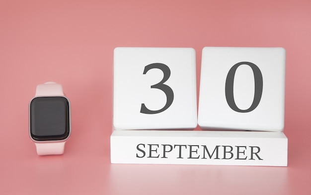 Moderne Uhr mit Würfelkalender und Datum 30. September auf rosa Wand. Konzept Herbstzeit Urlaub.