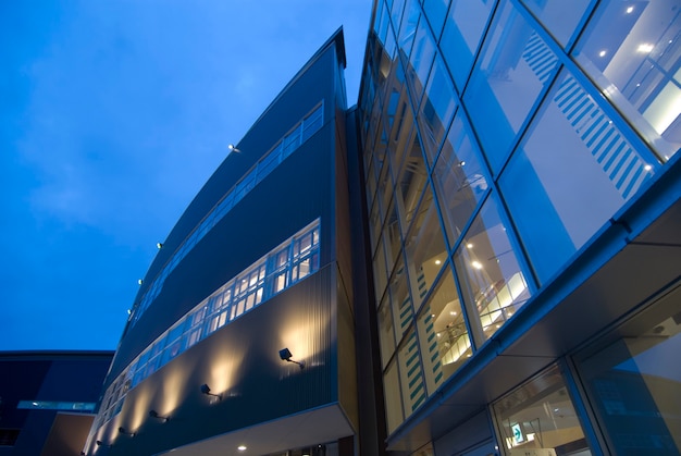 Moderner äußerer abstrakter architektonischer Hintergrund mit Wand- und Fensterbeleuchtung und blauem Himmel