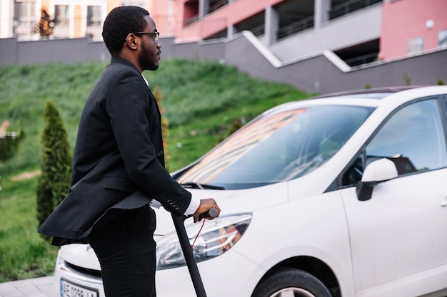 moderner afrikanisch-amerikanischer Geschäftsmann, der während einer Reise zur Arbeit in der Stadt einen Elektroroller fährt