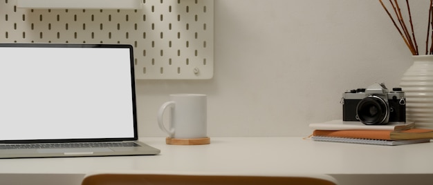 Moderner Arbeitsbereich mit Mock-up-Laptop, Kaffeetasse, Kamera, Zeitplanbüchern, Dekorationen