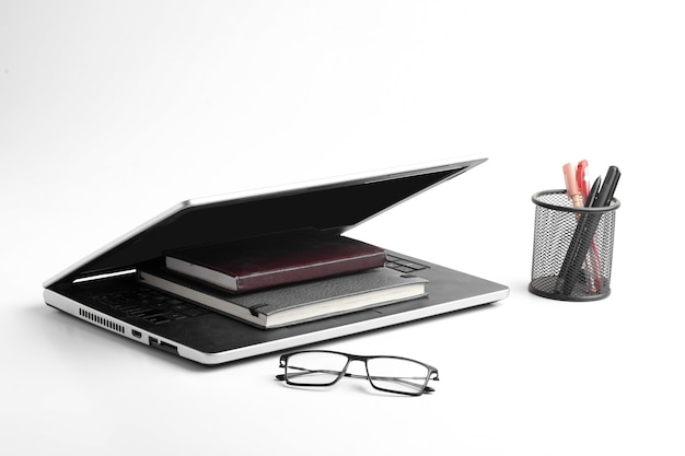 Moderner Arbeitsplatz mit Laptop-Tastatur, Notebook, Brille auf weißer Oberfläche.