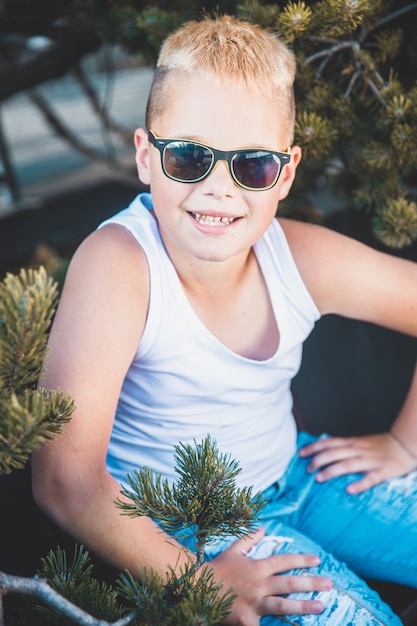 Foto moderner blonder junge mit dem sonnenbrillelächeln.