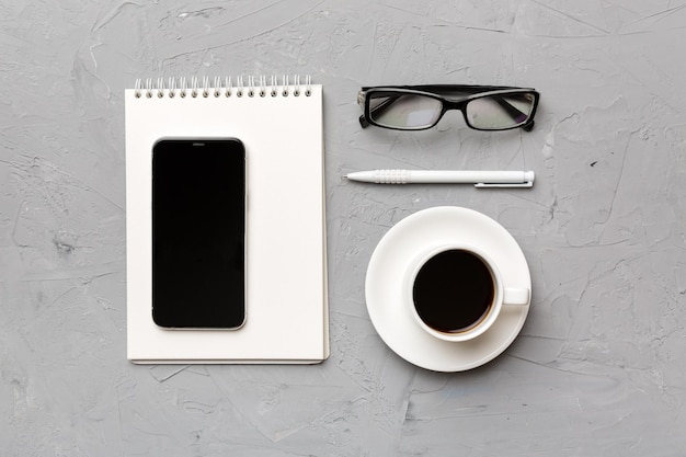 Moderner Büroschreibtisch mit Notebook-Smartphone und anderen Vorräten mit Tasse Kaffee Leere Notebook-Seite für Ihr Design Draufsicht flach liegend