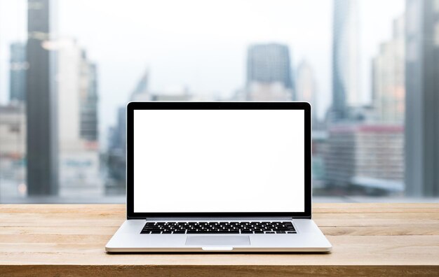 Moderner Computer-Laptop mit leerem Bildschirm auf Holztisch mit Blick auf das Bürofenster