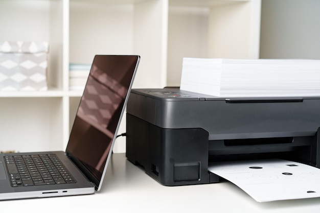 Foto moderner drucker mit papier und laptop auf dem tisch im büro