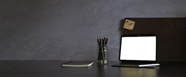 Moderner dunkler Arbeitsbereich mit Tablette und Stift auf schwarzem Tisch und Dachbodenwand