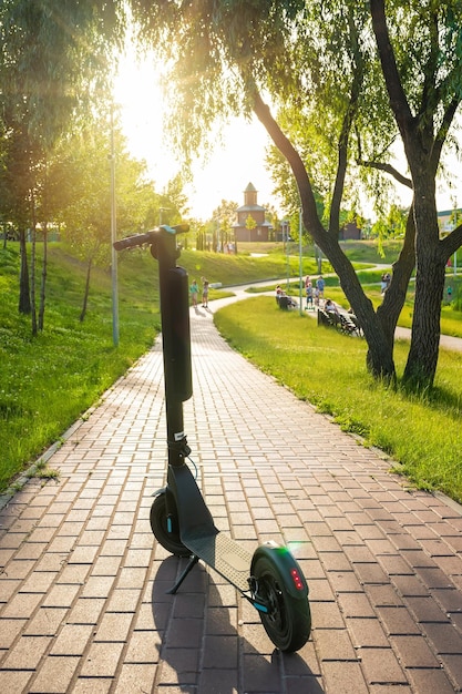 Moderner Elektroroller im Park an einem sonnigen Tag Ökologie und Umweltkonzept