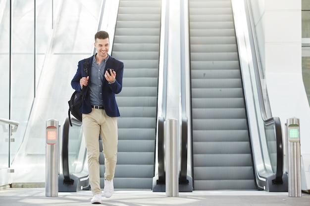 Moderner glücklicher Mann beim Telefonanruf durch Rolltreppe