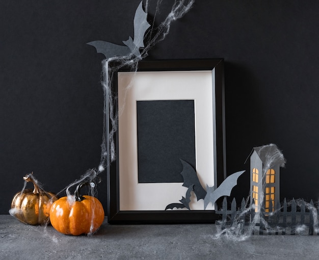 Moderner Halloween-Hintergrund mit Kürbissen, Fledermäusen und schwarzem Rahmen auf dunklem Hintergrund