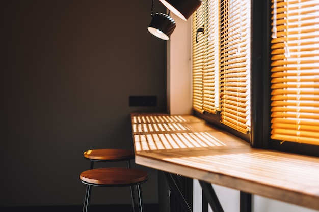 Moderner Holztisch auf der Küche nahe großem Fenster mit Vorhang