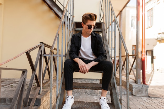 Moderner junger Hipster-Mann in der trendigen Sonnenbrille im stilvollen schwarzen Hemd