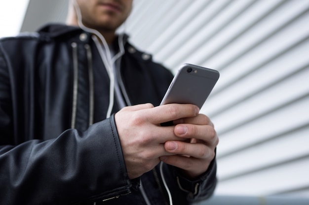 Moderner junger Mann mit seinem Handy auf der Straße.